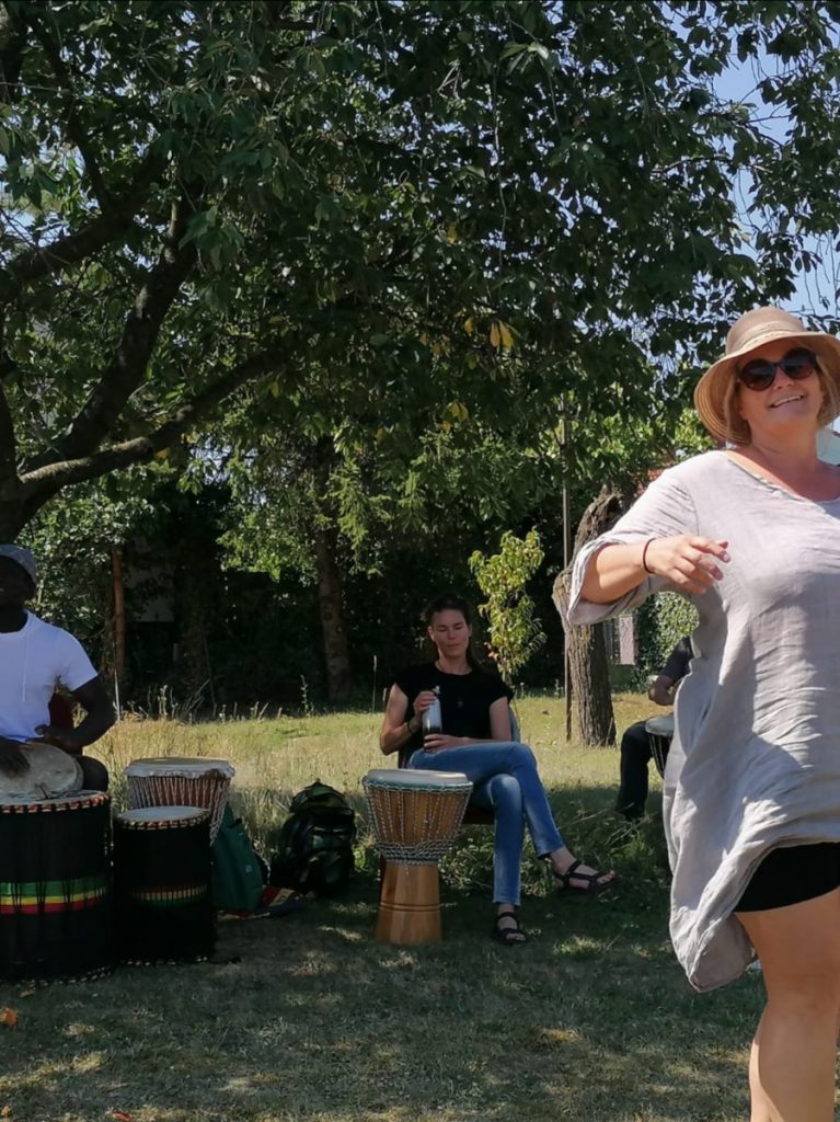 Eine tanzende Frau im Vordergrund, im Hintergrund eine afrikanischer Trommler