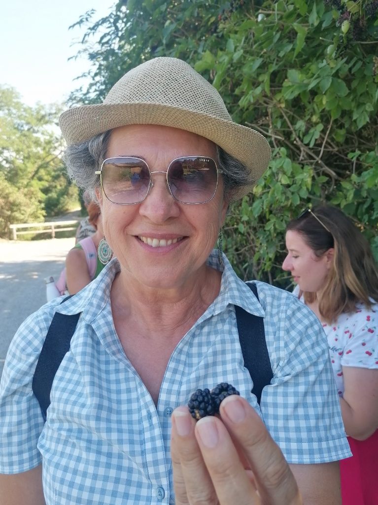 Frau mit Hut, Sonnenbrille, und Brombeeren in der Hand