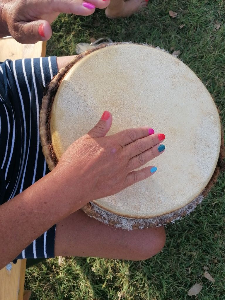 Hand mit bunten Fingernägeln auf Trommel