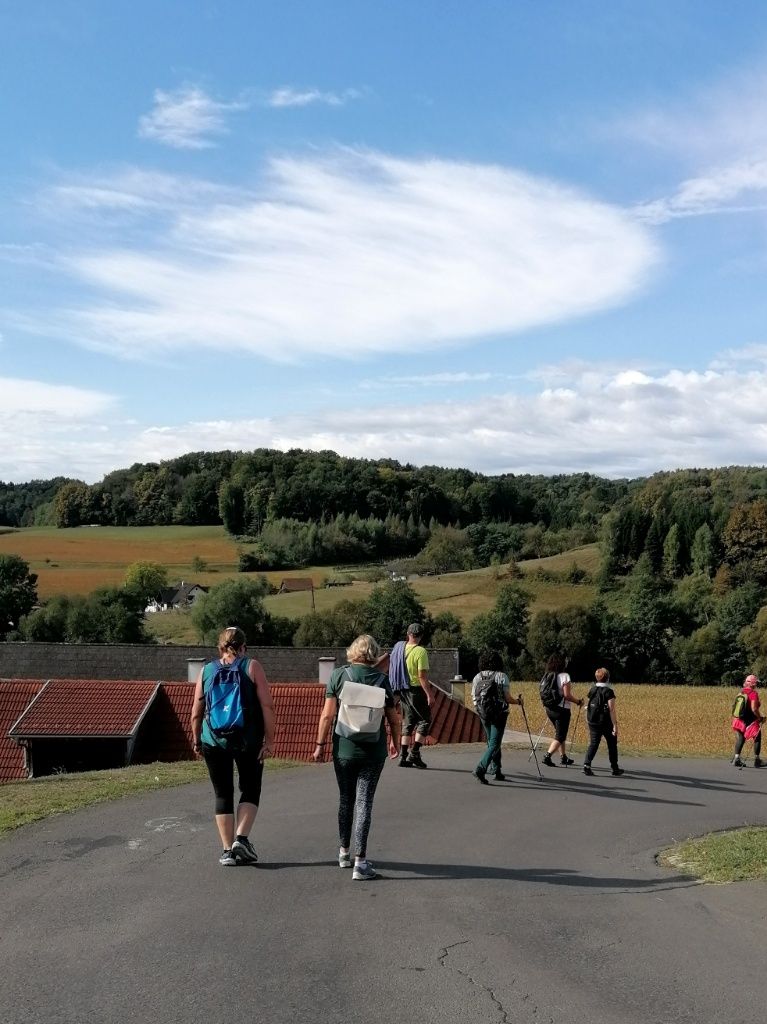 Fastengruppe marschiert auf der Straße, im Hintergrund Hügel und Himmel