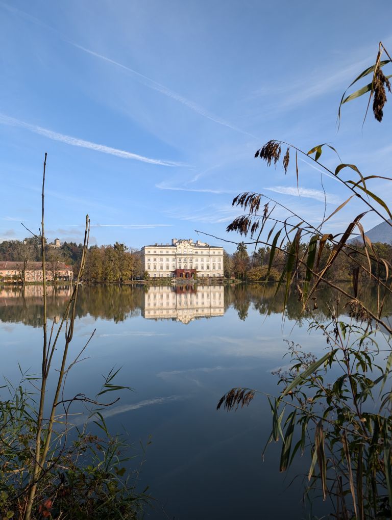 Blick auf das gegenüberliegende Ufer des Leopoldskroner Weiher auf das Schloss Leopoldskron, das sich im Wasser spiegelt