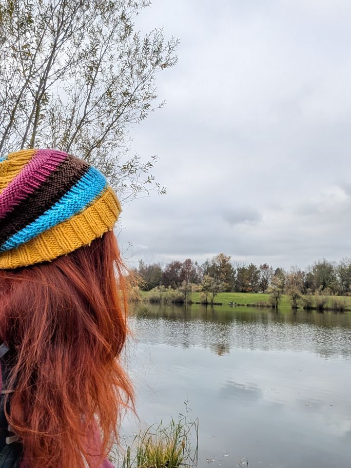 Karin von hinten mit bunt-gestreifter Haube und Blick auf einen der Salzachseen