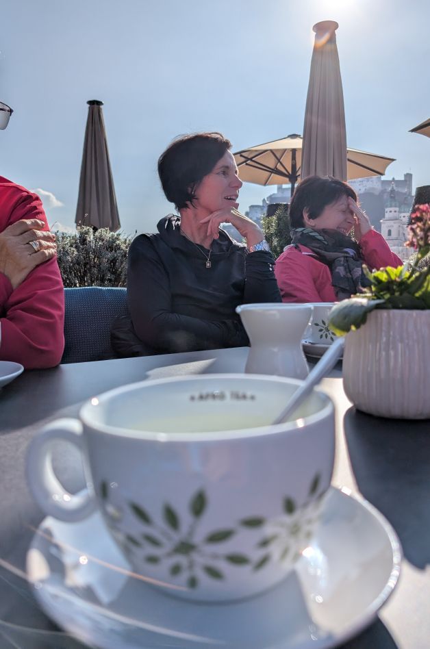 Teetasse im Vordergrund, im Hintergrund zwei Frauen und strahlender Himmel