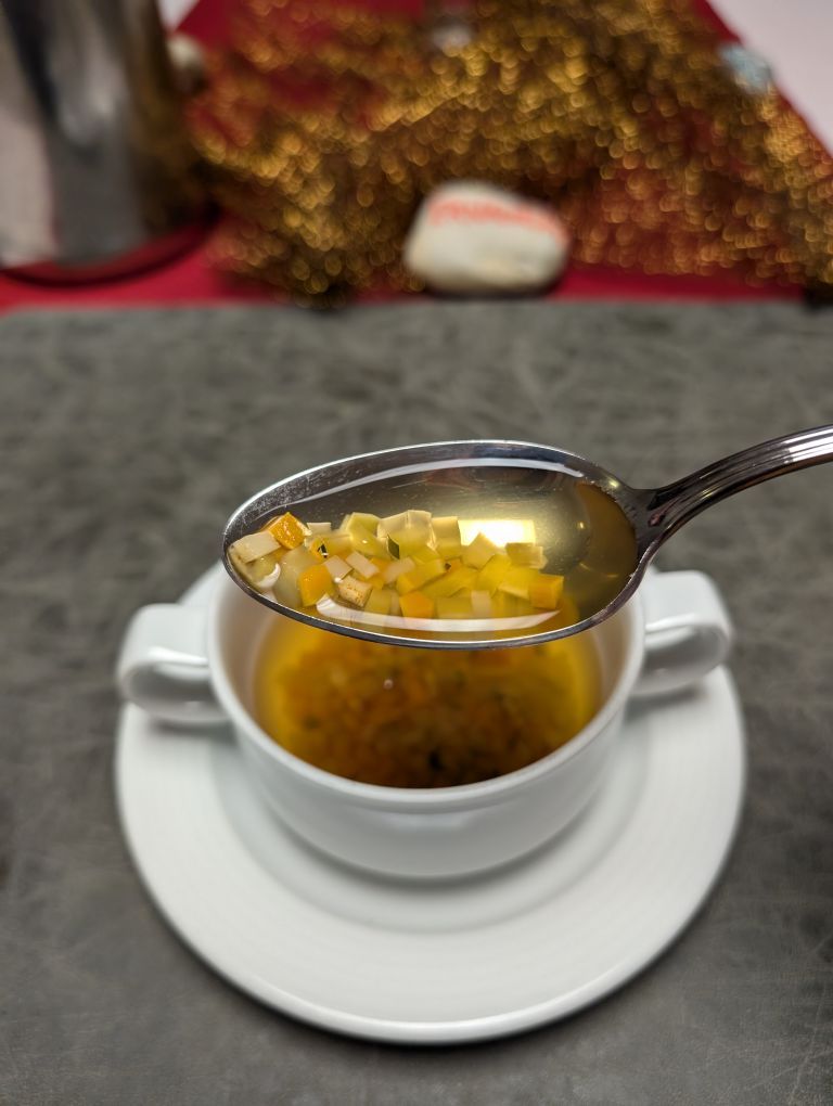 Suppenschale mit Gemüsesuppe, am Löffel Gemüsestücke